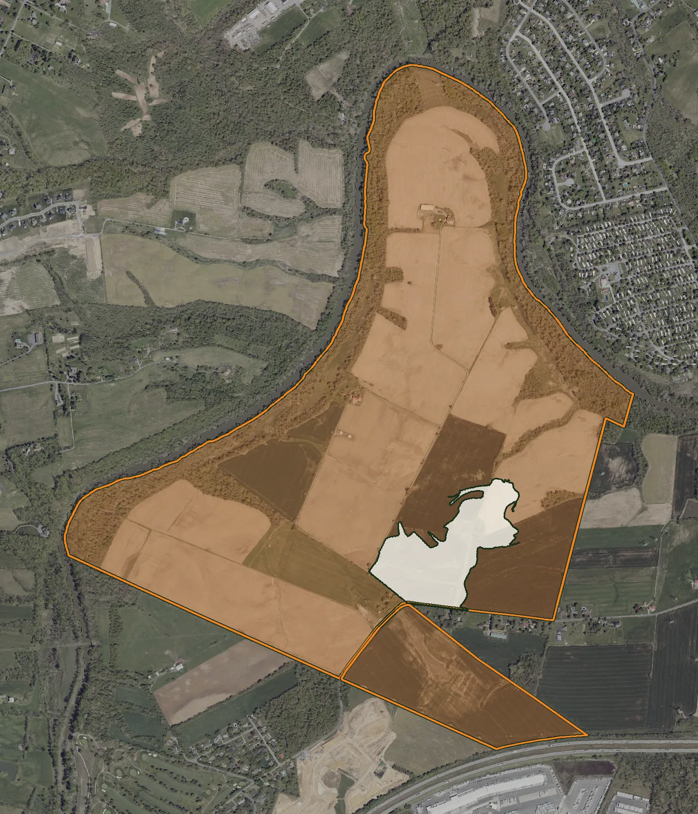 An aerial photo of the PAX-1 site. A small area in the southeast, shaded cream, is where the stormwater permit applied from 2018 to December 2025: 36 acres for the Cumberland Knoll subdivision. The whole site, outlined and shaded orange, is where it applies now: 693 acres.
